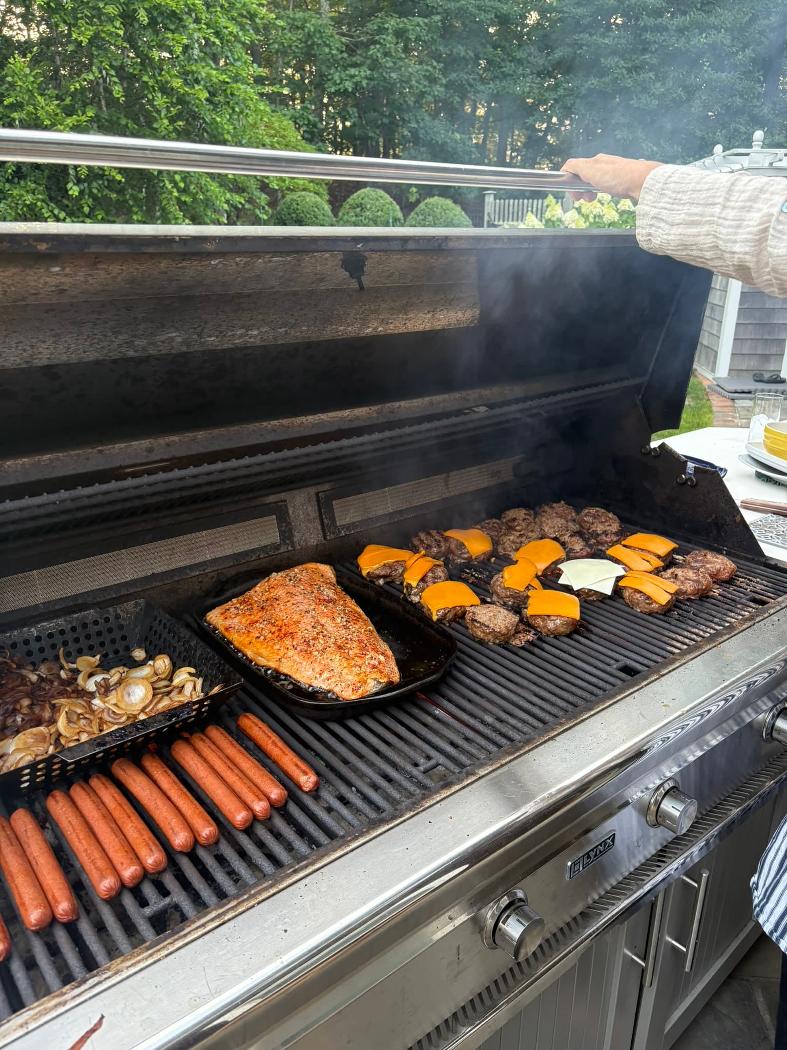 Salmon, burgers, vegetables, and hot dogs cooking on the grill